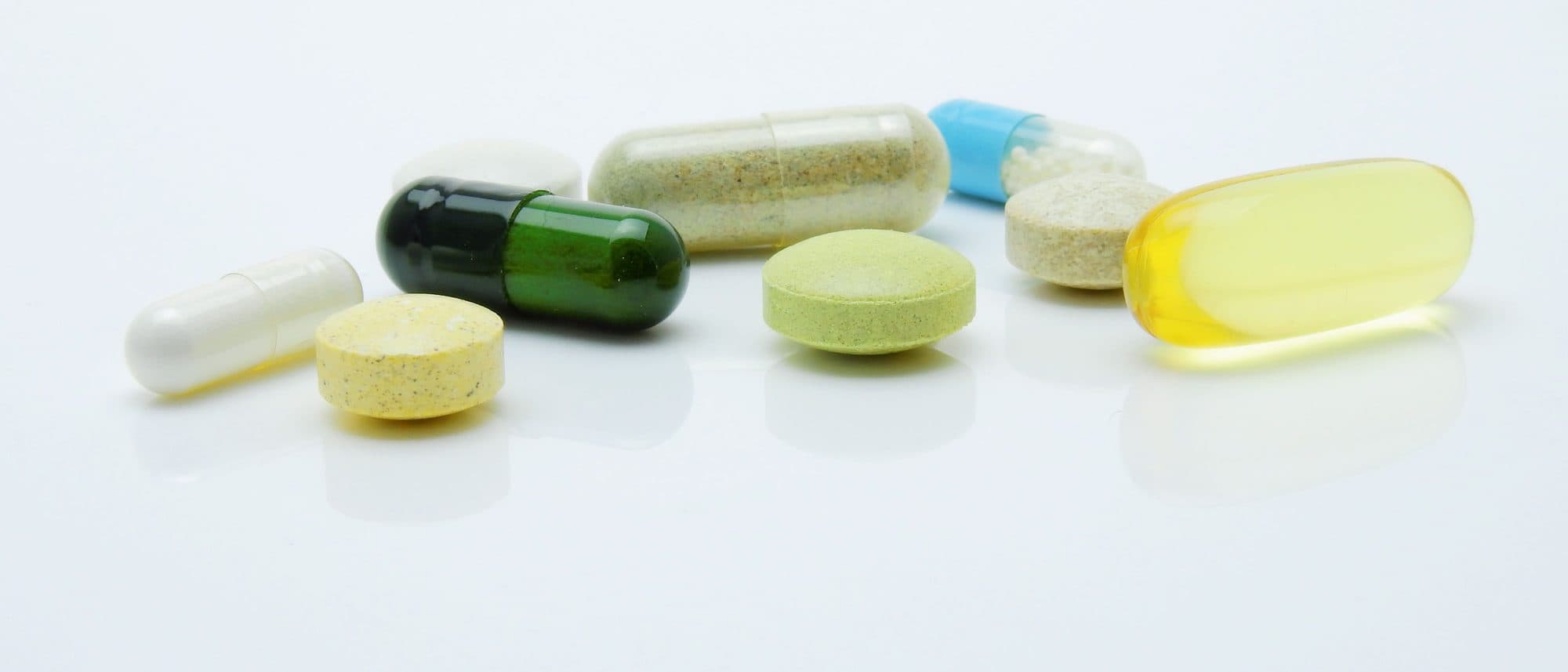 Capsules, tablets and softgels in a range of formats and colours on a white surface.