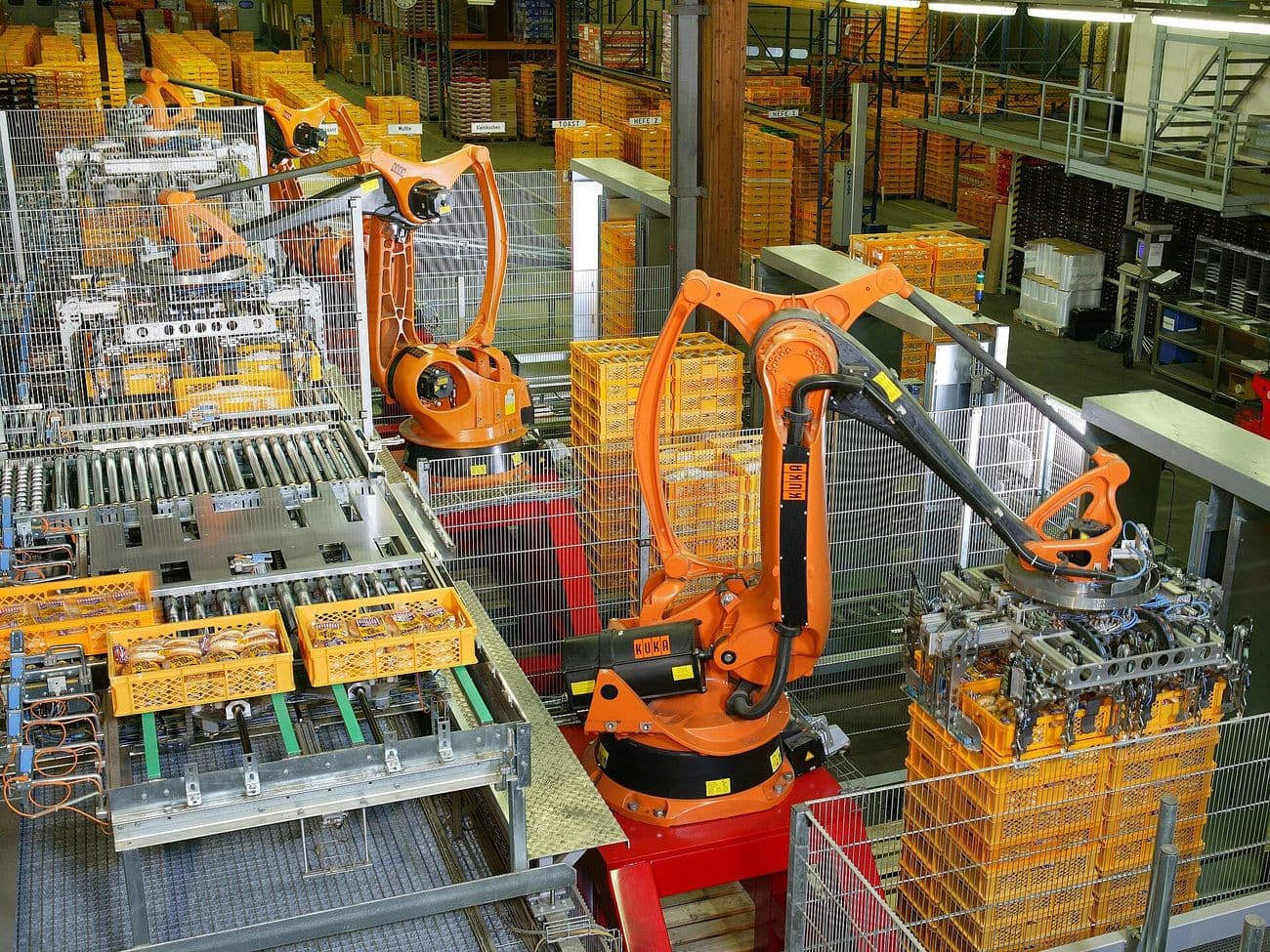 Robots palletising crates of packed goods at the end of a production line.
