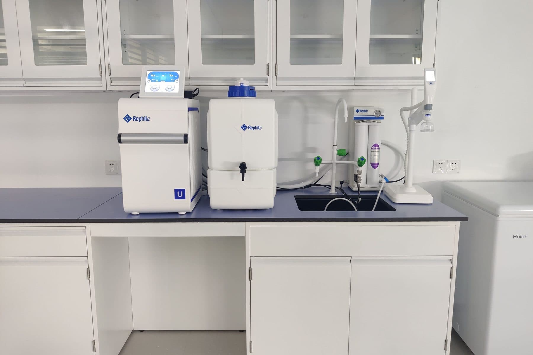 A laboratory bench with water-purification equipment and glass-fronted cabinets.
